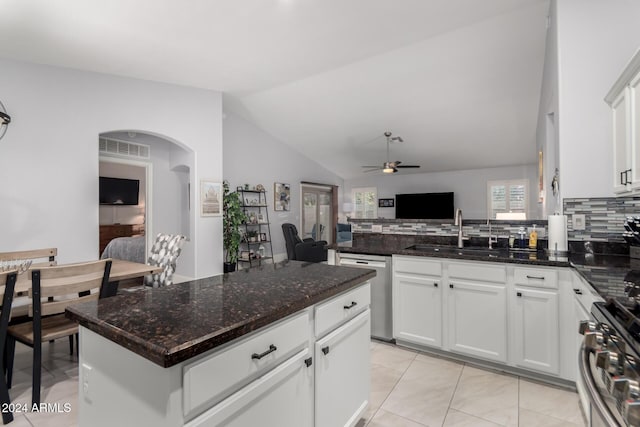 kitchen featuring white cabinetry, sink, stainless steel appliances, dark stone counters, and lofted ceiling