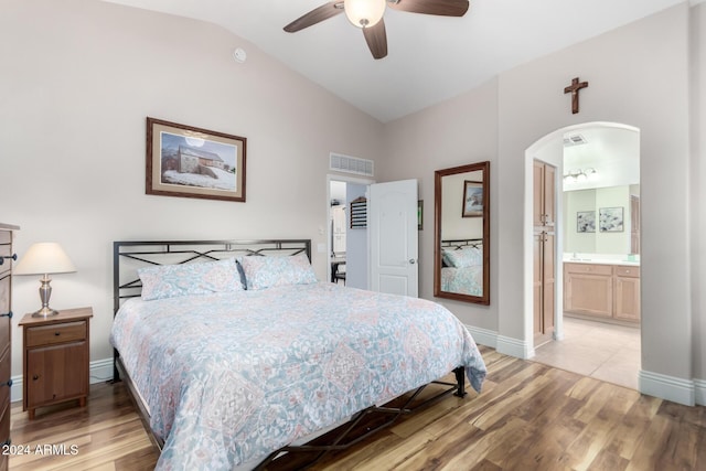 bedroom with connected bathroom, light hardwood / wood-style floors, vaulted ceiling, and ceiling fan