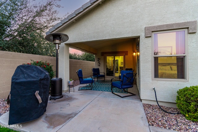 patio terrace at dusk with outdoor lounge area and a grill