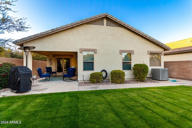 back of house featuring a lawn, a patio, and central AC