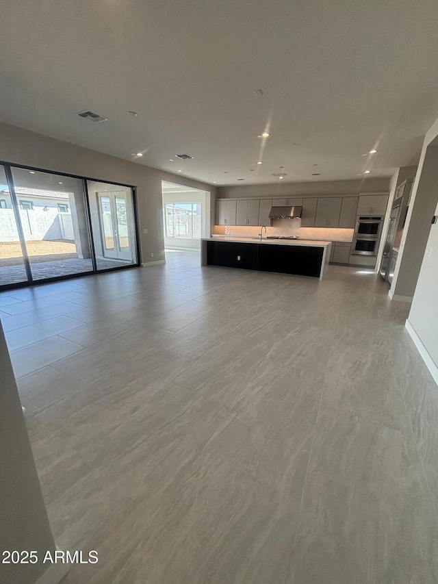 unfurnished living room with visible vents, recessed lighting, baseboards, and a sink