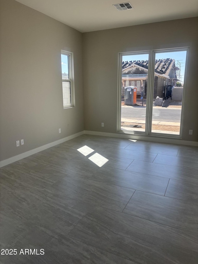 empty room with visible vents, baseboards, and a healthy amount of sunlight