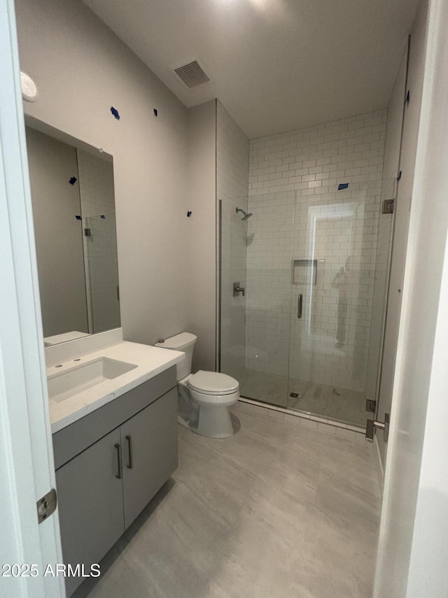 bathroom with visible vents, a shower stall, vanity, and toilet