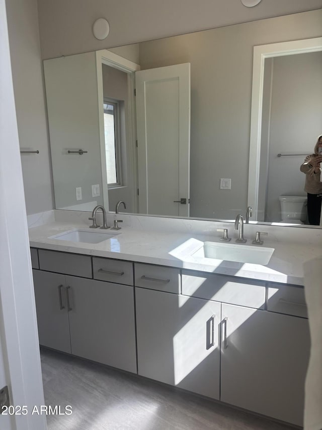 bathroom featuring double vanity, toilet, and a sink