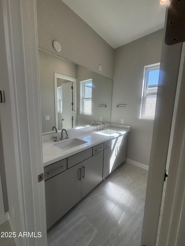 bathroom with a sink, baseboards, and double vanity