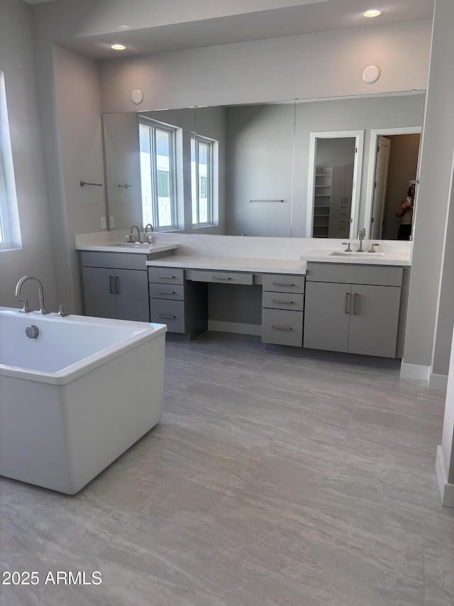 bathroom with recessed lighting, a soaking tub, and vanity