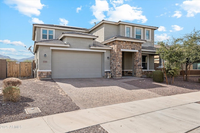 view of front of home featuring stone siding, stucco siding, decorative driveway, and roof mounted solar panels