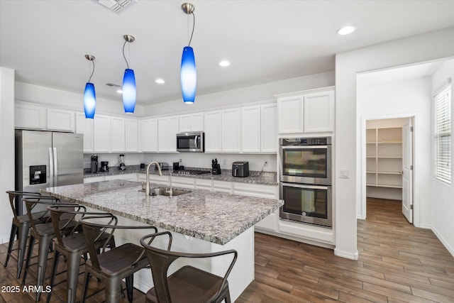 kitchen featuring visible vents, dark wood finished floors, a sink, stainless steel appliances, and white cabinetry