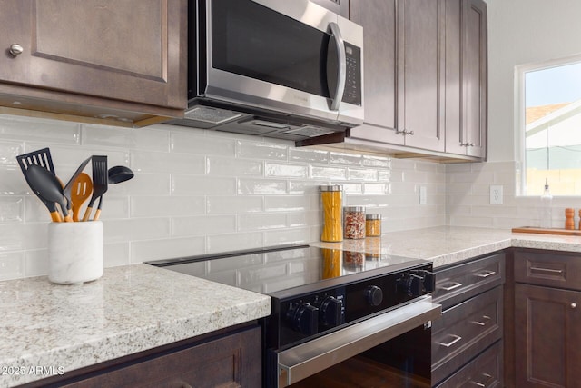 kitchen with tasteful backsplash, light stone countertops, black electric range oven, and dark brown cabinetry