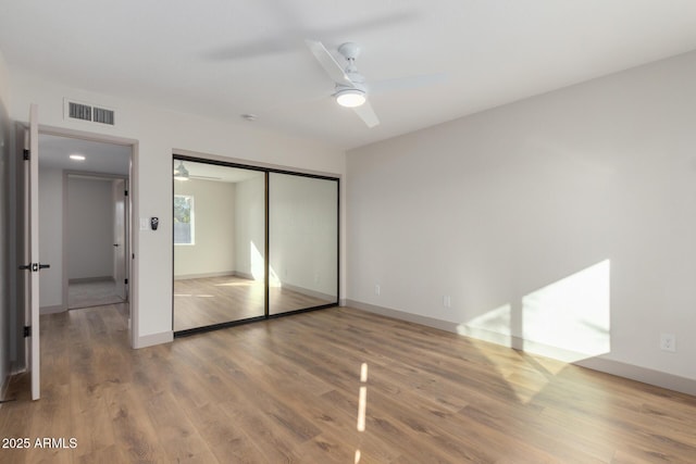 unfurnished bedroom with hardwood / wood-style flooring, a closet, and ceiling fan