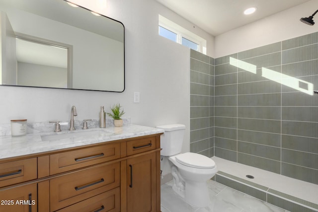 bathroom with vanity, toilet, and a tile shower