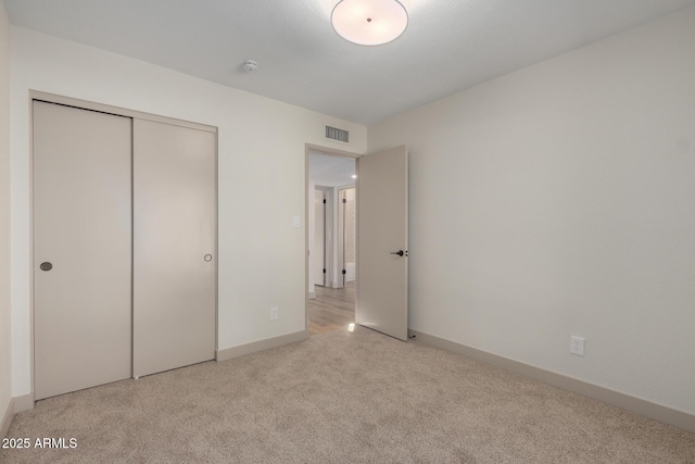 unfurnished bedroom featuring a closet and light carpet