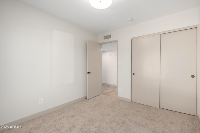 unfurnished bedroom featuring light colored carpet and a closet