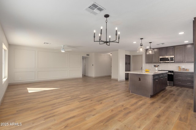 kitchen featuring pendant lighting, dark brown cabinetry, appliances with stainless steel finishes, and a kitchen island