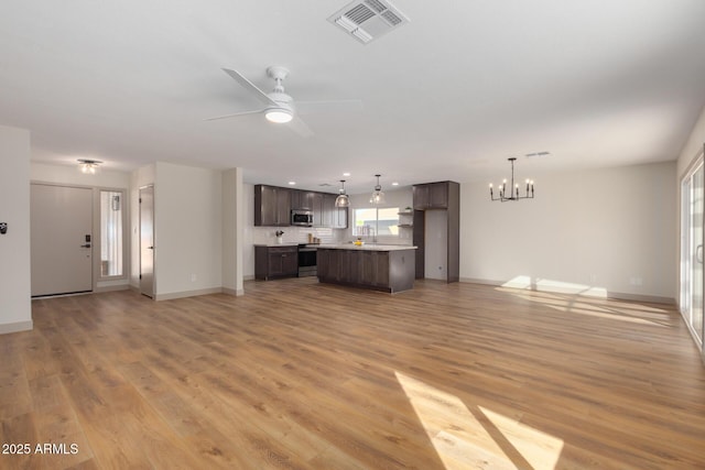 unfurnished living room with ceiling fan with notable chandelier and light hardwood / wood-style floors