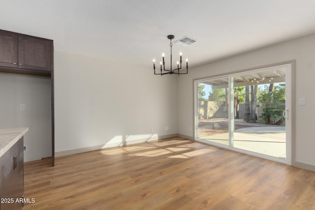 unfurnished dining area with a chandelier and light wood-type flooring