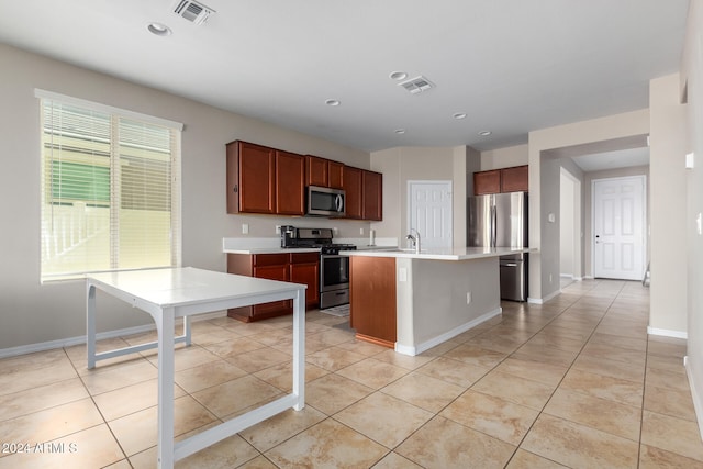 kitchen with a breakfast bar area, appliances with stainless steel finishes, an island with sink, light tile patterned flooring, and sink