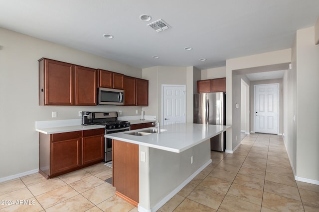 kitchen with light tile patterned floors, appliances with stainless steel finishes, sink, a breakfast bar, and a kitchen island with sink