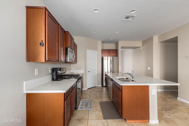 kitchen featuring light tile patterned floors, stainless steel appliances, sink, and a center island with sink