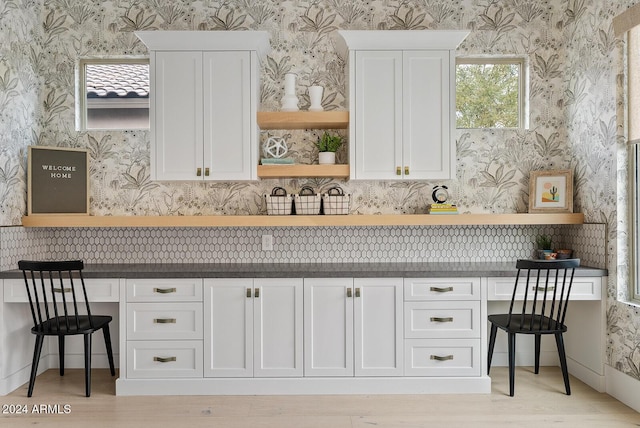 kitchen featuring white cabinetry, built in desk, a breakfast bar, and light hardwood / wood-style flooring