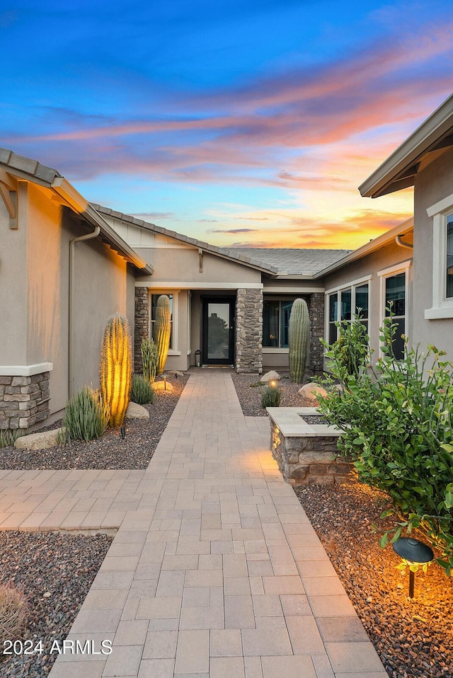 exterior entry at dusk featuring a patio