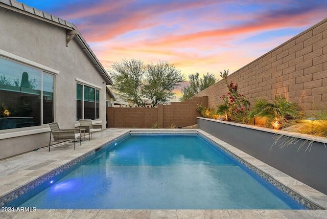 pool at dusk featuring a patio area