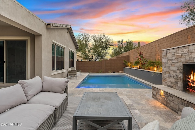 pool at dusk featuring a patio area and an outdoor living space with a fireplace