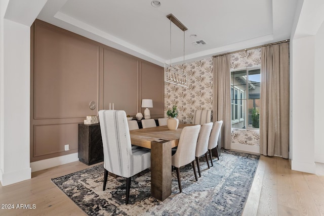 dining area with a tray ceiling and light hardwood / wood-style flooring