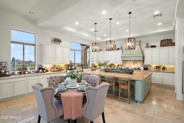 10799 E Florence Way, Scottsdale, AZ 85262 - dining space with visible vents, a tray ceiling, a high ceiling, and stone tile flooring