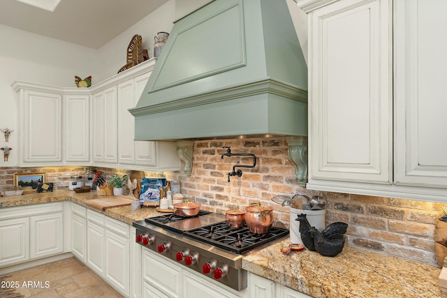 10799 E Florence Way, Scottsdale, AZ 85262 - kitchen featuring stainless steel gas cooktop, stone finish floor, premium range hood, and white cabinetry