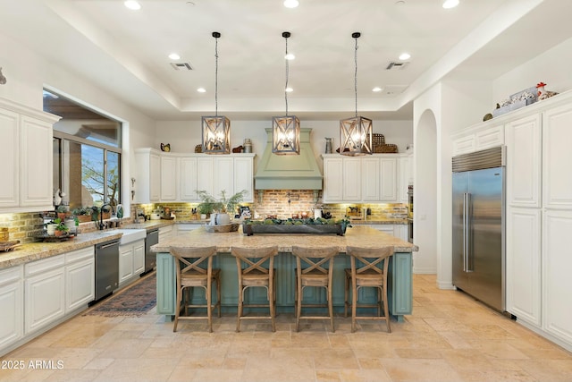 10799 E Florence Way, Scottsdale, AZ 85262 - kitchen featuring a tray ceiling, arched walkways, visible vents, a center island, and stainless steel appliances