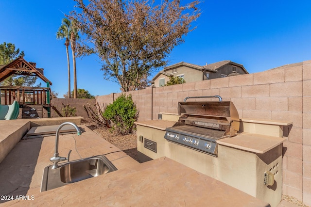 view of patio featuring a grill, area for grilling, a playground, and sink