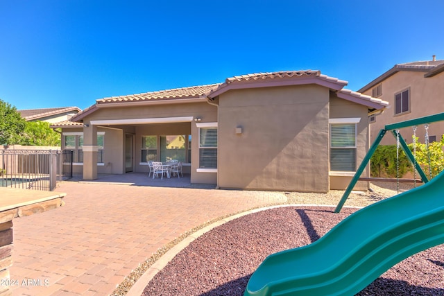 rear view of property with a playground and a patio