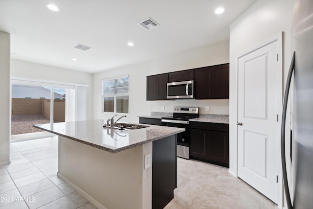 5516 E Mearn Rd, San Tan Valley, AZ 85140 - kitchen with stainless steel appliances, a sink, light stone counters, a center island with sink, and light tile patterned floors