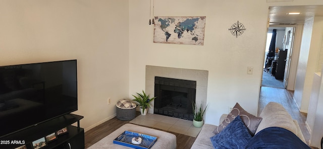 living room featuring a tiled fireplace and wood-type flooring