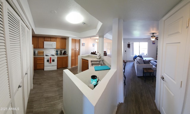 kitchen featuring a textured ceiling, white appliances, ceiling fan, sink, and dark hardwood / wood-style floors