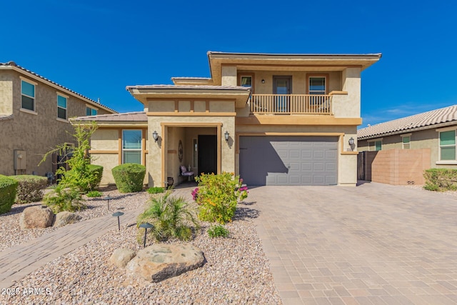 view of front of property with a garage, decorative driveway, a balcony, and stucco siding