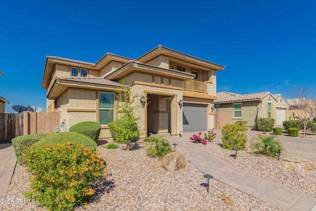 prairie-style home with driveway, fence, a balcony, and stucco siding