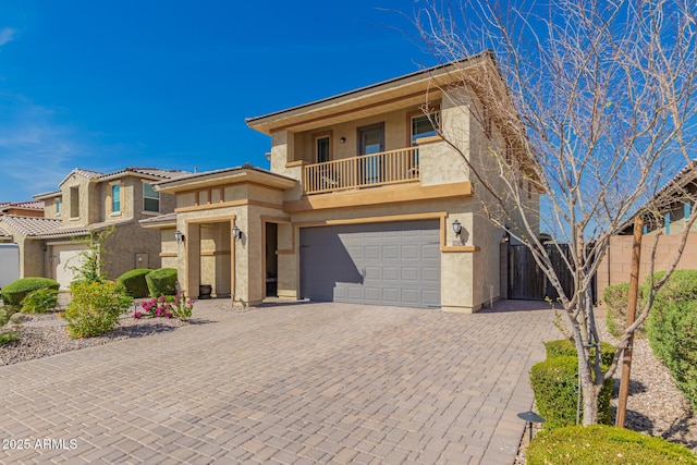 view of front facade with decorative driveway, a balcony, and stucco siding