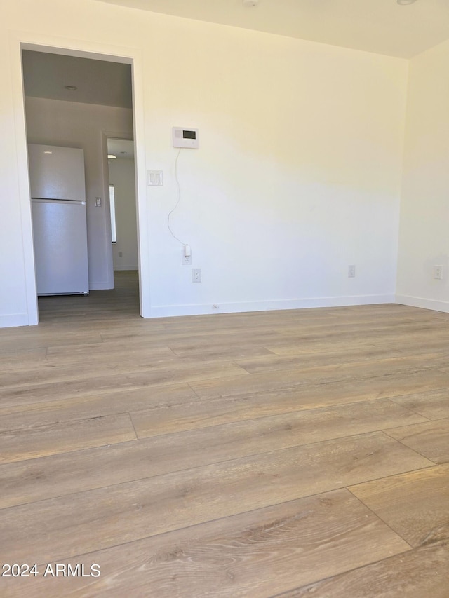 unfurnished room with light wood-type flooring and baseboards