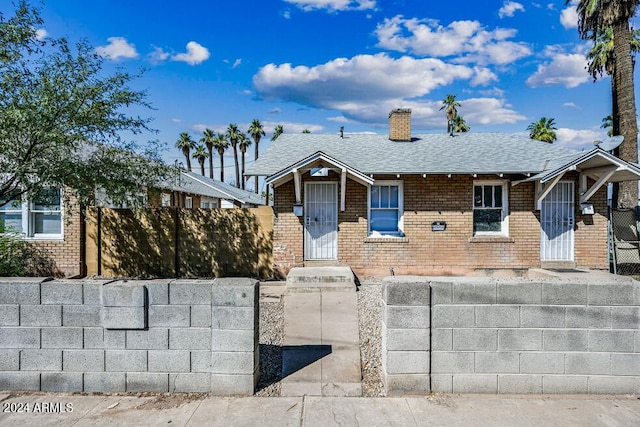 single story home featuring fence, brick siding, roof with shingles, and a chimney