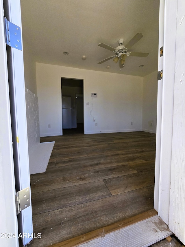 spare room featuring dark wood finished floors, a ceiling fan, and baseboards