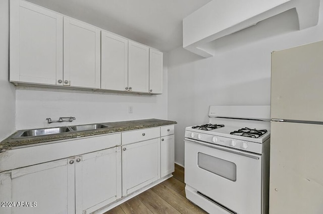 kitchen featuring a sink, white appliances, wood finished floors, and white cabinetry