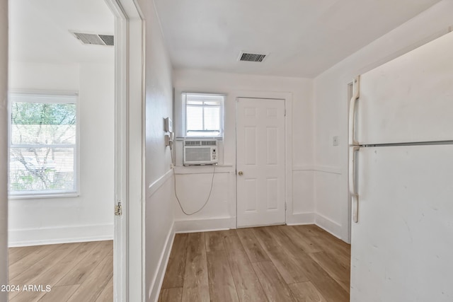 interior space with cooling unit, baseboards, visible vents, and light wood finished floors