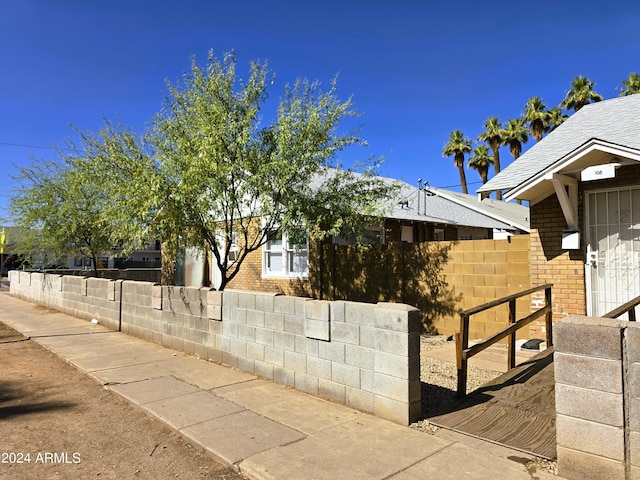 view of side of property featuring brick siding and fence