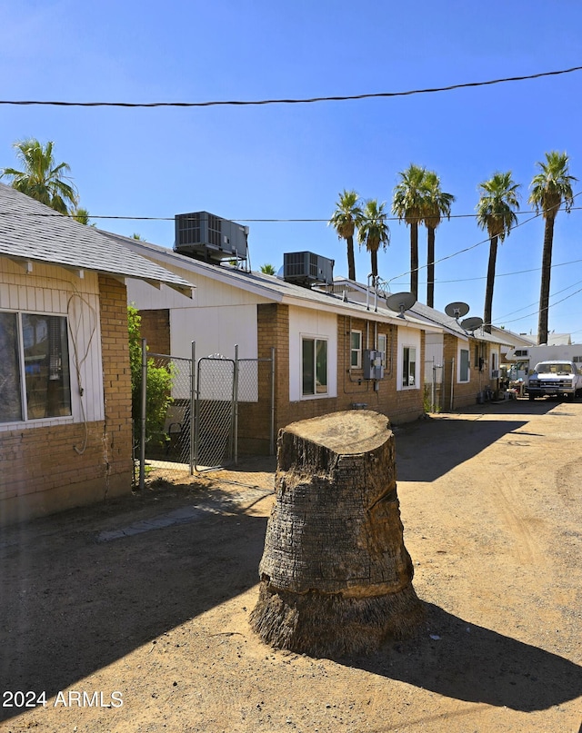 exterior space featuring a gate, brick siding, central AC, and fence