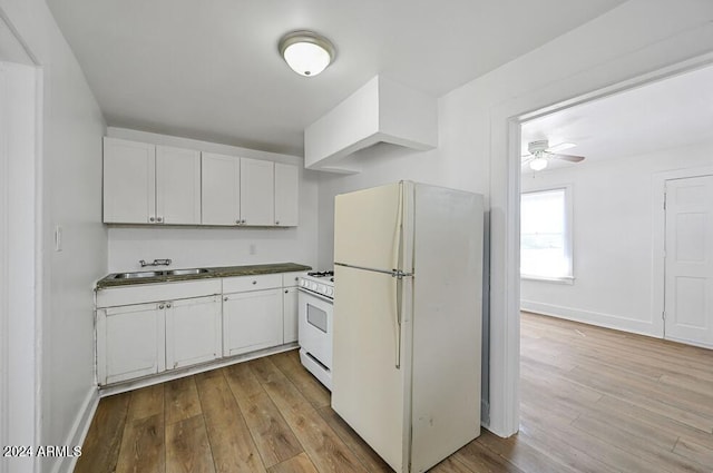 kitchen with a sink, white appliances, light wood-style floors, and white cabinets