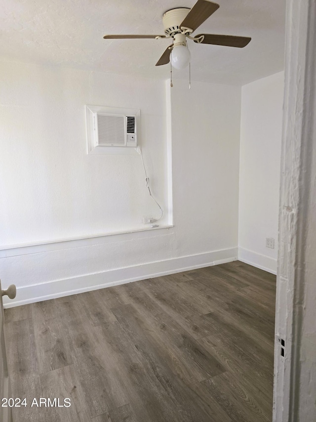 spare room featuring an AC wall unit, wood finished floors, and baseboards