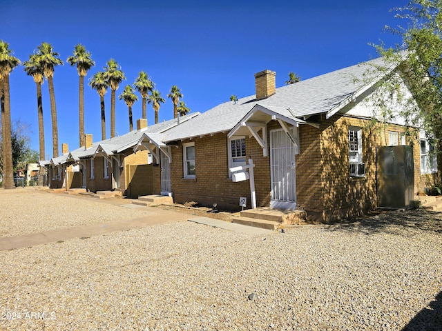 view of front of home featuring brick siding and a chimney