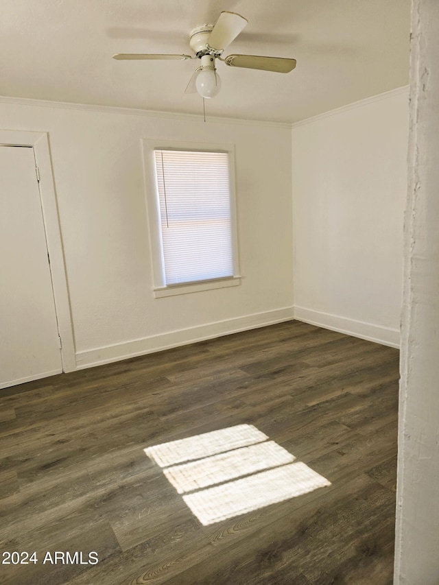 empty room featuring dark wood-style floors, a ceiling fan, baseboards, and ornamental molding